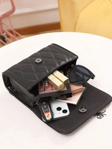 Quilted black leather flap bag with V-shaped tassel showing spacious interior storage
