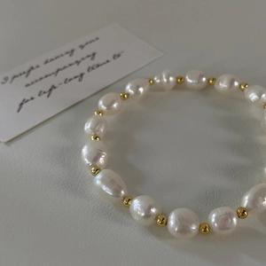 Macro shot of irregular freshwater pearls and gold beads on a minimalist elastic bracelet