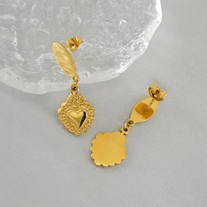 Détails macro de boucles d'oreilles cœur dorées avec texture martelée et polie du métal