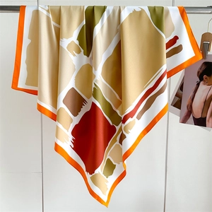 Detail of geometric color block twill silk scarf showing smooth texture and orange hem