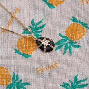 Detailed shot of black enamel teardrop pendant with gold plating and colorful crystals