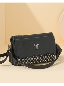 Detail of black leather crossbody bag featuring rhinestone studs and rabbit metal hardware