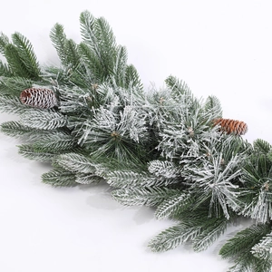 Close-up of artificial green Christmas garland with white flocking and pine cones
