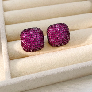 Détail des boucles d'oreilles carrées pavées de zircons violets sur métal noir poli