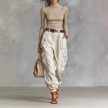 Dettaglio dei pantaloni cargo color crema con tasche multiple e cintura in marrone