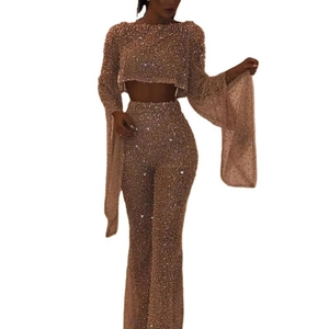 Detail of glittery long sleeve crop top and flared trousers set in champagne gold color