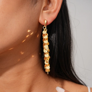 Gros plan de boucles d'oreilles longues à franges dorées avec paillettes en métal poli