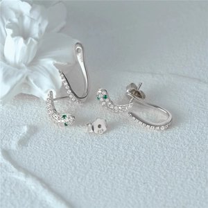 Close-up of S925 sterling silver snake earrings with pavé diamonds and green gem eyes