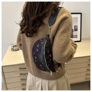 Detail of black canvas cherry print crossbody bag with gold hardware and wide strap