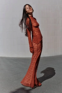 Détail de la dentelle marron rouge sur une robe maxi transparente à col montant