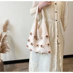 Detail of cream knit tote bag featuring dark brown floral crochet patterns and soft texture