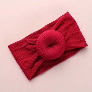 Detail of red cable-knit nylon baby headband with a donut knot on a pink background