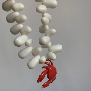 Detailed close-up of white beads and red crab pendant on a nautical choker necklace
