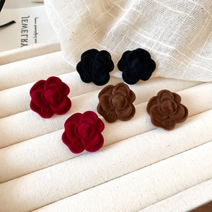 Macro shot of flocked camellia flower stud earrings in black, wine red, and brown