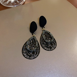 Macro shot of vintage black matte earrings with teardrop filigree and crystal inlay