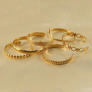 Detail of six gold-plated stainless steel bangles with diverse textured patterns