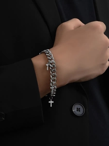 Detail shot of silver Cuban link bracelet with cross pendants on a male model