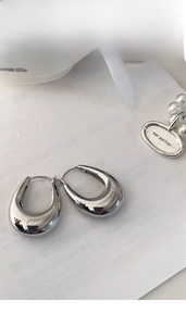 Detail of silver drop earrings with a polished finish and thick U-shape design