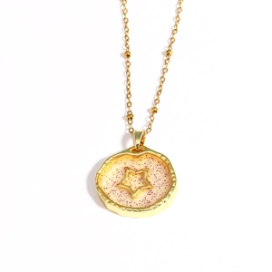 Detail of gold star and pink glitter inside a round pendant necklace with fine gold chain