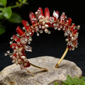 Detailed shot of golden floral crown with pink crystals and pearls on a stone base