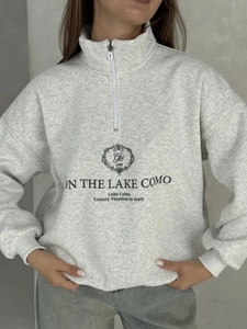 Close-up of vintage grey half-zip sweatshirt featuring black letter print and soft cotton fabric