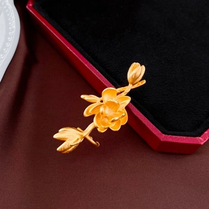Détail macro d'une broche fleurie en or mat avec une texture florale sur tissu de soie