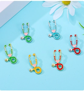 Vue à plat de broches stéthoscope colorées en émail sur un fond bleu clair