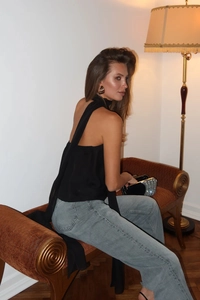 Detailansicht eines schwarzen Neckholder-Tops mit langen Bändern und hellblauer Jeanshose