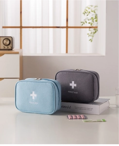 Close-up of portable first aid bags with zipper and cross symbol on a white desk