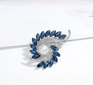 Detail of a rotating flower brooch with a large white pearl and blue marquise crystals