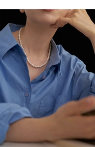 Close-up of elegant pearl beaded necklace worn with a blue shirt for a vintage style