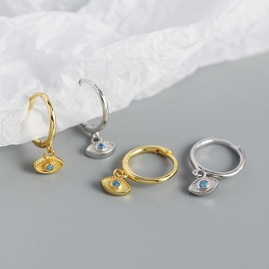 Macro shot of gold and silver S925 sterling silver evil eye hoop earrings set with blue gems