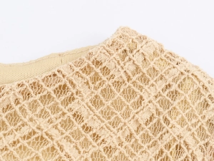 Macro shot of beige knitted lace fabric showing intricate diamond texture and fine mesh detail