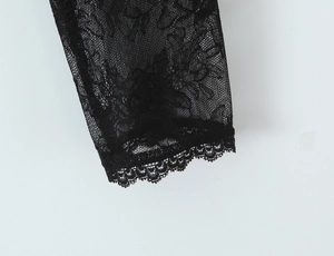 Close-up of black floral lace fabric with intricate mesh details and scalloped hem edge