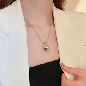 Detailed view of silver teardrop pendant and snake chain necklace on model neck