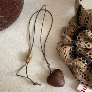 Retro brown wooden heart pendant necklace with bamboo accents on beige linen background