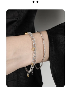 Close-up of a double-layered chain bracelet with a gold pendant on a model's wrist