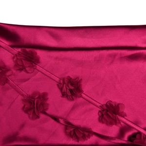 Détail du tissu en satin rose foncé avec fleurs 3D et rubans élégants sur la robe