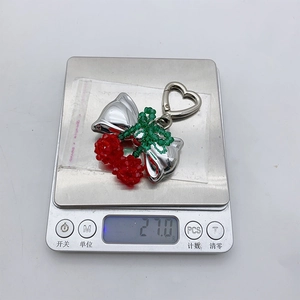 Close-up of handmade cherry keychain with silver bow showing 2.10g weight on scale