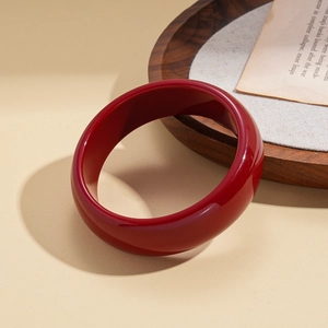 Close-up of deep red resin geometric round bangle on a vintage paper background