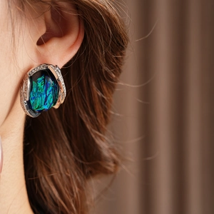 Close-up of vintage resin earring with blue-green gemstone and sparkling rhinestones