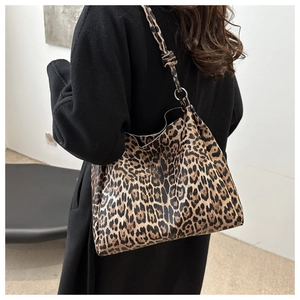 Detailed back view of a leopard print tote bag with metal ring strap on a black coat