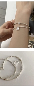 Detailed macro view of silver heart pendant and square plate charm bracelet with engraving