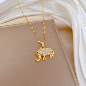 Close-up of golden elephant pendant with clear crystals on white silk background