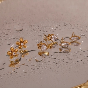 Macro shot of 18K gold plated stainless steel floral and crown stud earrings with crystals