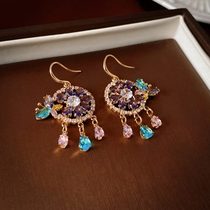 Close-up of gold flower earrings with colorful zircons and drop gems on a jewelry tray