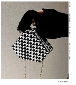 Detail of houndstooth triangle bag featuring faux fur handle and golden metal chain