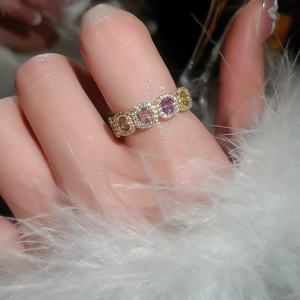 Close-up of 14k gold plated ring with colorful zircon square stones on white feathers