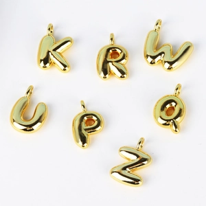 Detail of 3D bubble style gold letter pendants with polished metallic finish