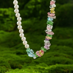 Short necklace featuring white pearls and colorful gemstones on mossy background